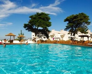 Una piscina al aire libre, sombrillas, tumbonas