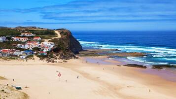 A coastal town with houses on a cliff overlooking the beach.