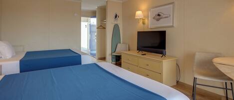 Een hotelkamer met twee bedden, een televisie, een bureau en een stoel.