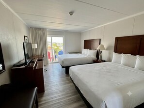 A hotel room with two beds, a desk with a computer, a TV, and a balcony with a view. - Flamingo Motel (Ocean City)