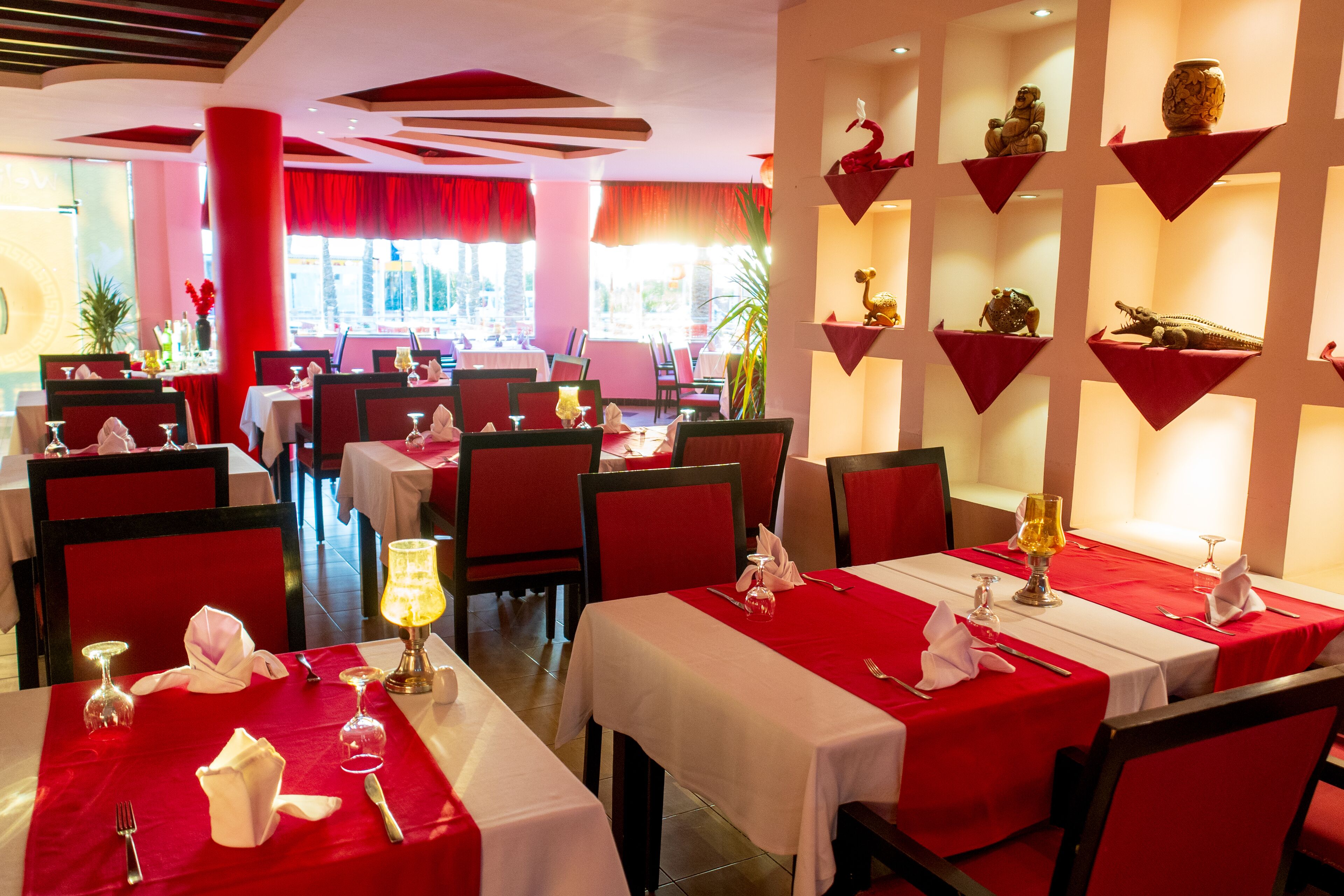 A restaurant with red and white decor, multiple dining tables, and a view of the outside.