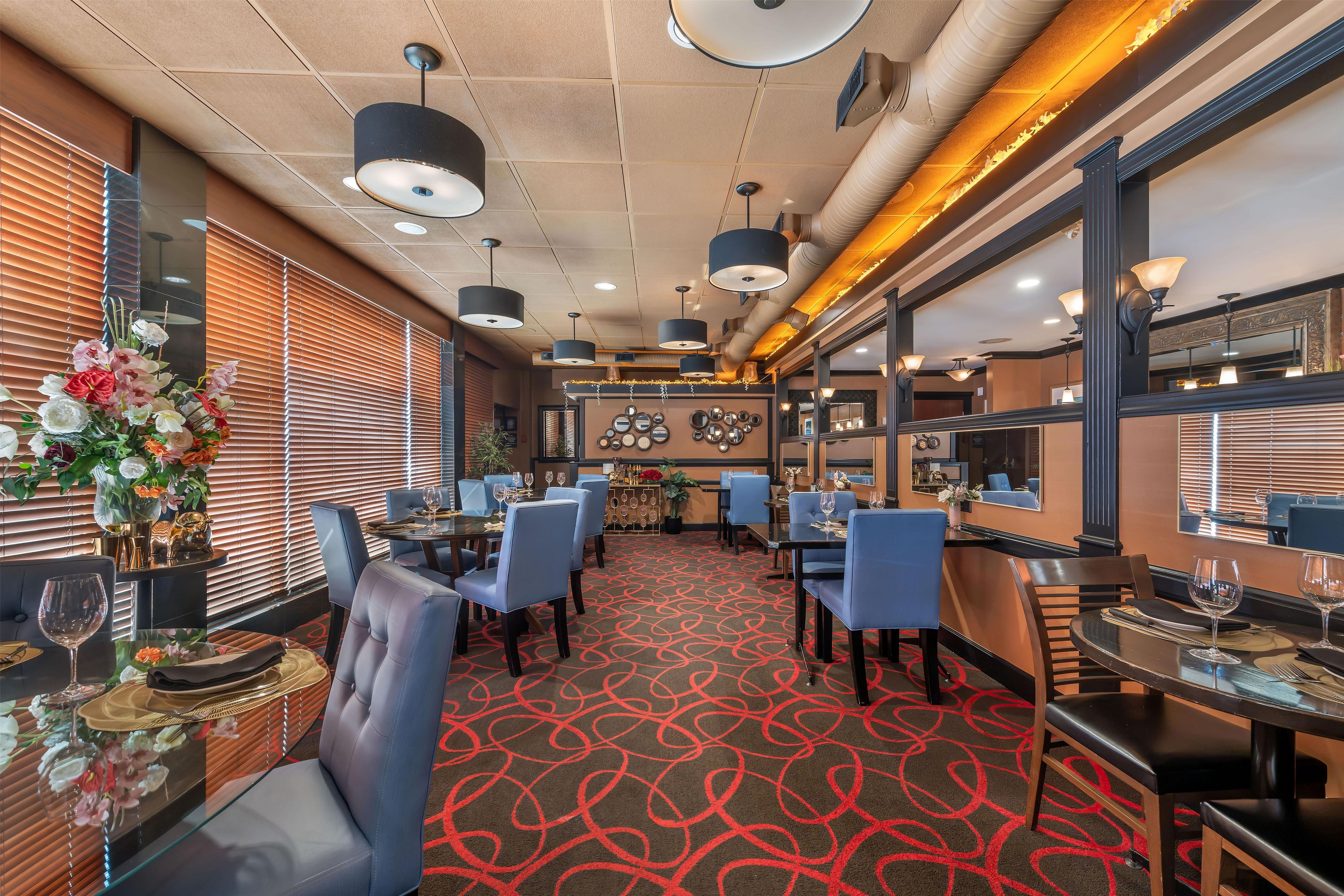 A hotel dining area with tables, chairs, and a patterned carpet.