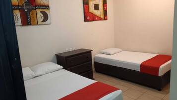 A hotel room with two beds, a dresser, and two abstract paintings on the wall.