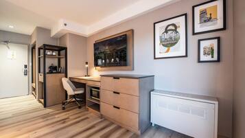 A modern office space with a desk, chair, and storage unit. There are framed pictures on the wall and a large window with a view of a bridge.