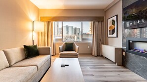 A modern hotel room with a sofa, armchair, and a fireplace. - Park Town Hotel (Saskatoon)
