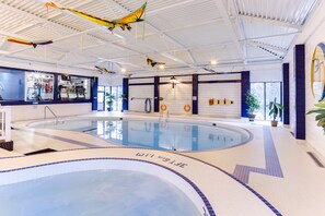 An indoor swimming pool with a clear water surface, a ladder, and a tiled floor with directional arrows. - Park Town Hotel (Saskatoon)