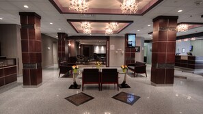 A lobby with a reception desk, seating area, and a television screen. - Park Town Hotel (Saskatoon)