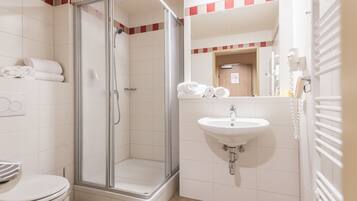 A bathroom with a glass-enclosed shower, a sink, and a toilet.