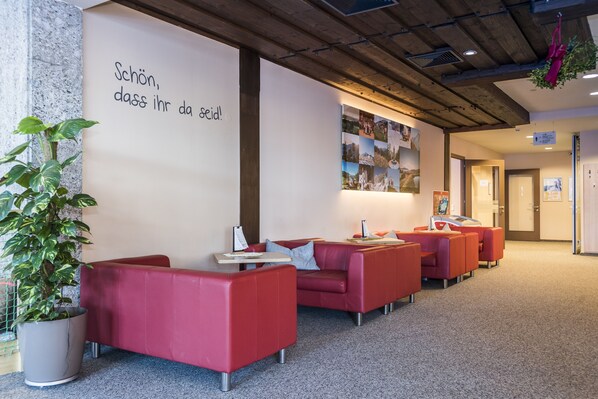 A modern lobby with red seating, a large wall with a message, and a plant. - JUFA Hotel Altenmarkt (Altenmarkt im Pongau)