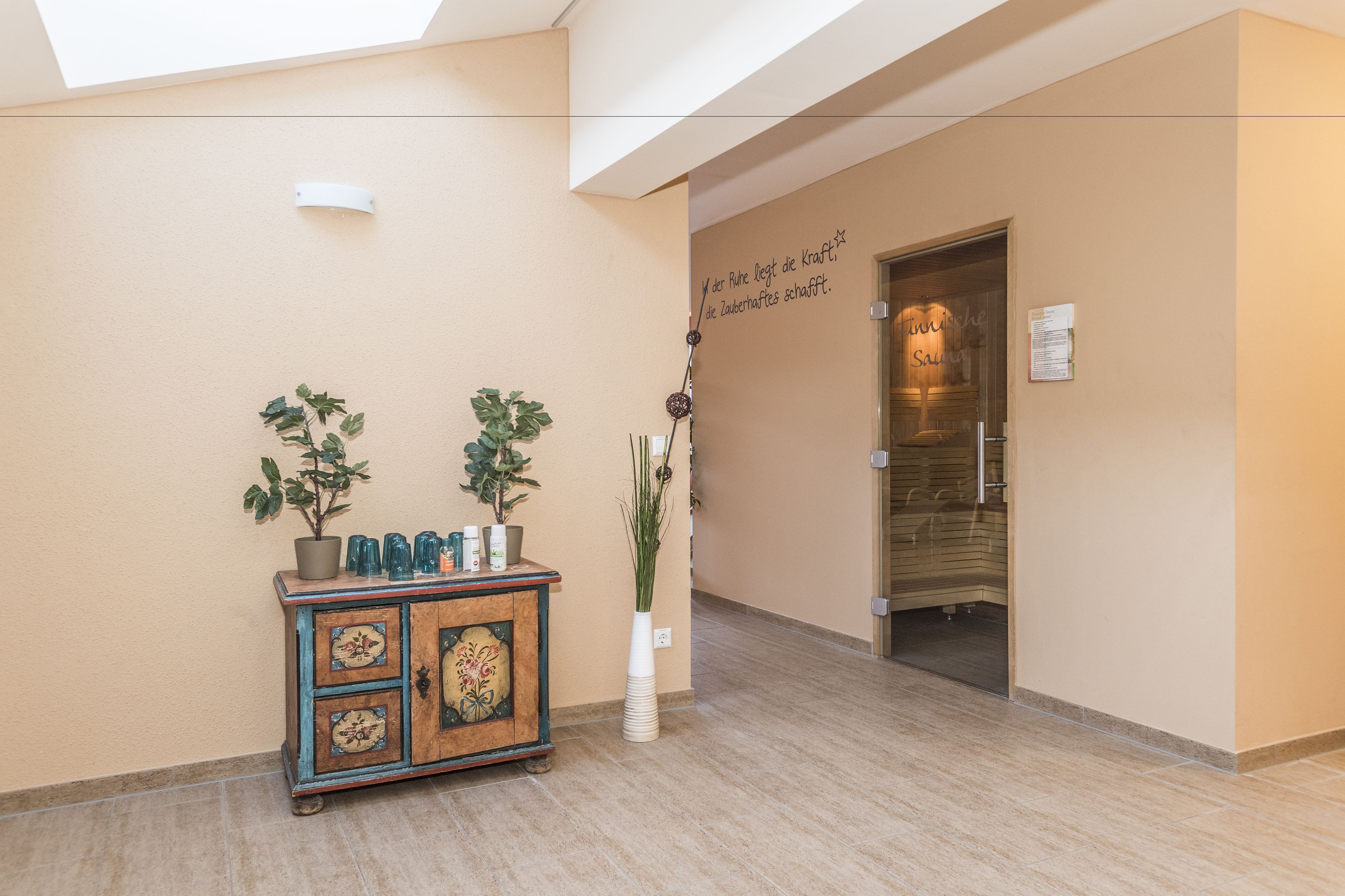 A reception area with a wooden cabinet, potted plants, and a wall with a motivational quote.