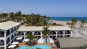 Un hotel con piscina, vista sulla spiaggia e diversi balconi.