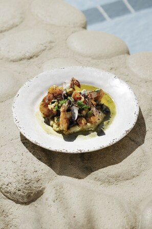 A seafood dish on a white plate with a stone background. - La Marina Inn (San José del Cabo)