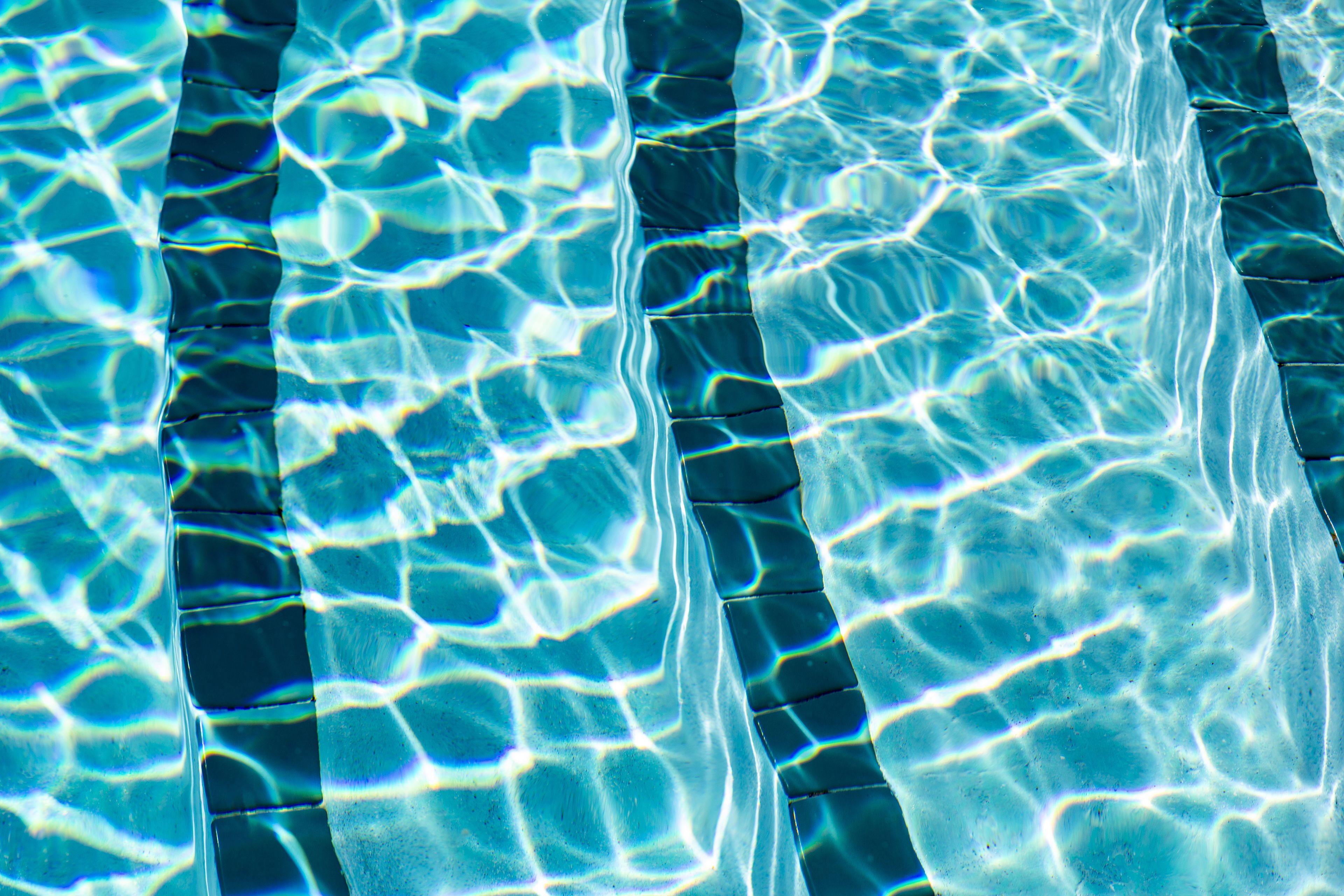 Una piscina con agua cristalina y líneas de azulejos visibles.