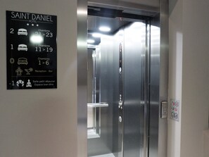 An elevator with a sign indicating Saint Daniel Hotel, with floor numbers and room types. - Hôtel Saint Daniel (Peruwelz)