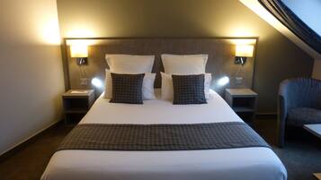 A hotel room with a large bed, two bedside lamps, a chair, and a view of the sky.