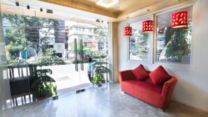 A modern lobby with a red sofa, glass doors, and potted plants. - De-Oriell-Boutique Hotel (Bengaluru)