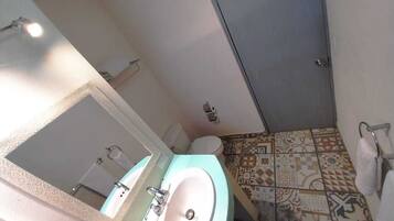 A bathroom with a sink, mirror, toilet, and patterned floor tiles.