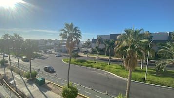 Una carretera con varios carriles, palmeras y edificios al fondo.