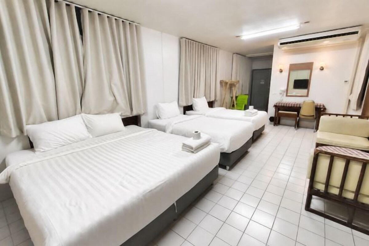 A hotel room with two beds, a desk, a chair, and a small seating area.