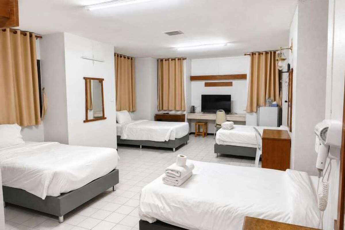 A hotel room with two beds, a desk, a TV, and a hairdryer.