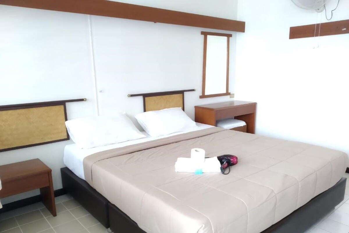 Une chambre d’hôtel avec un lit, une table de chevet et un miroir.