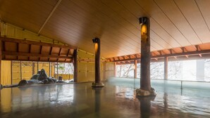 A traditional Japanese building with a wooden interior, stone pillars, and a view of snow-covered trees outside. - Jozankei View Hotel (Sapporo)