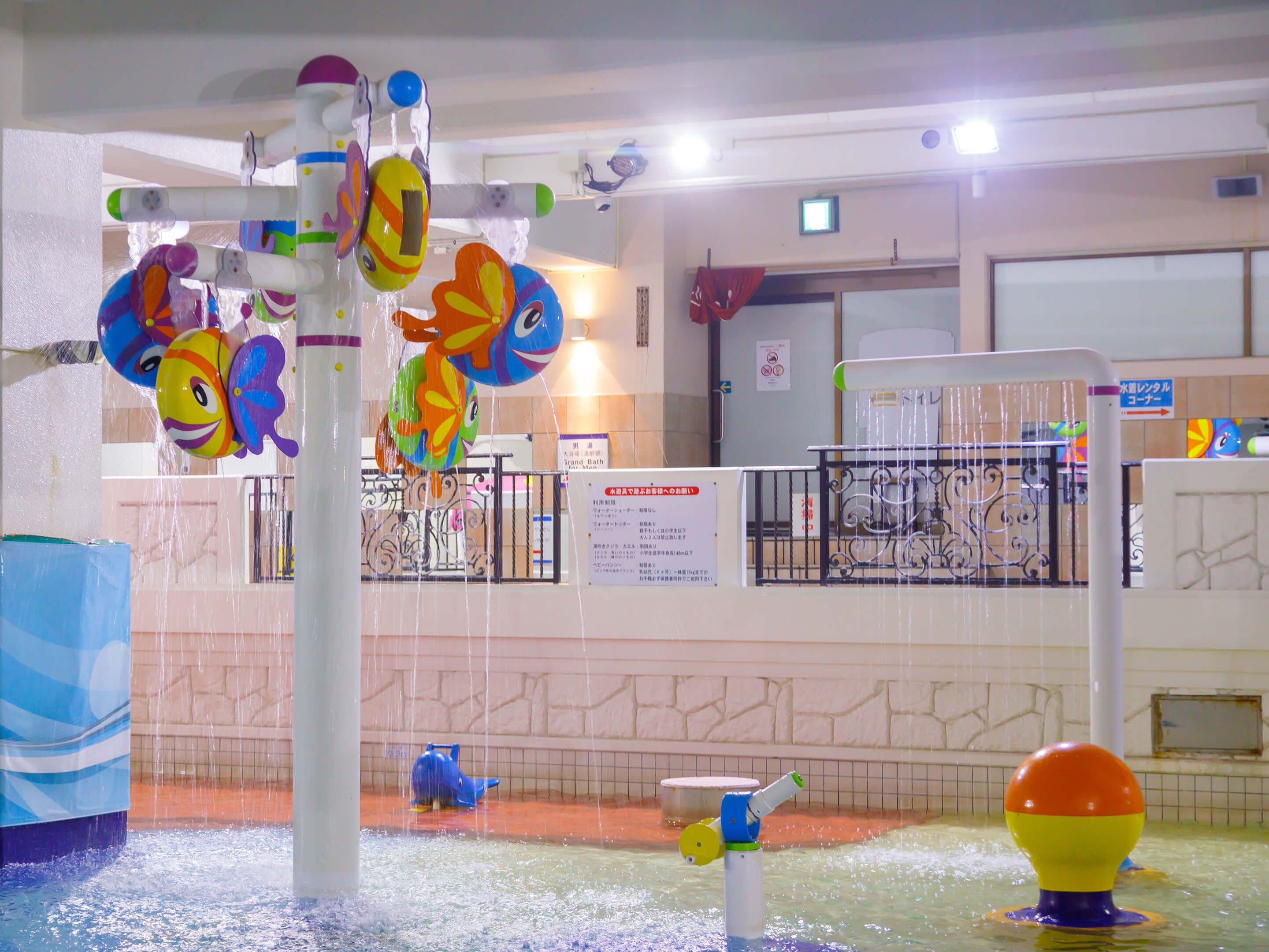 Un espace de jeux aquatiques doté de plusieurs éléments ludiques, notamment une fontaine et un toboggan aquatique.