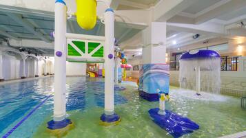 An indoor swimming pool with water slides and a colorful play area.