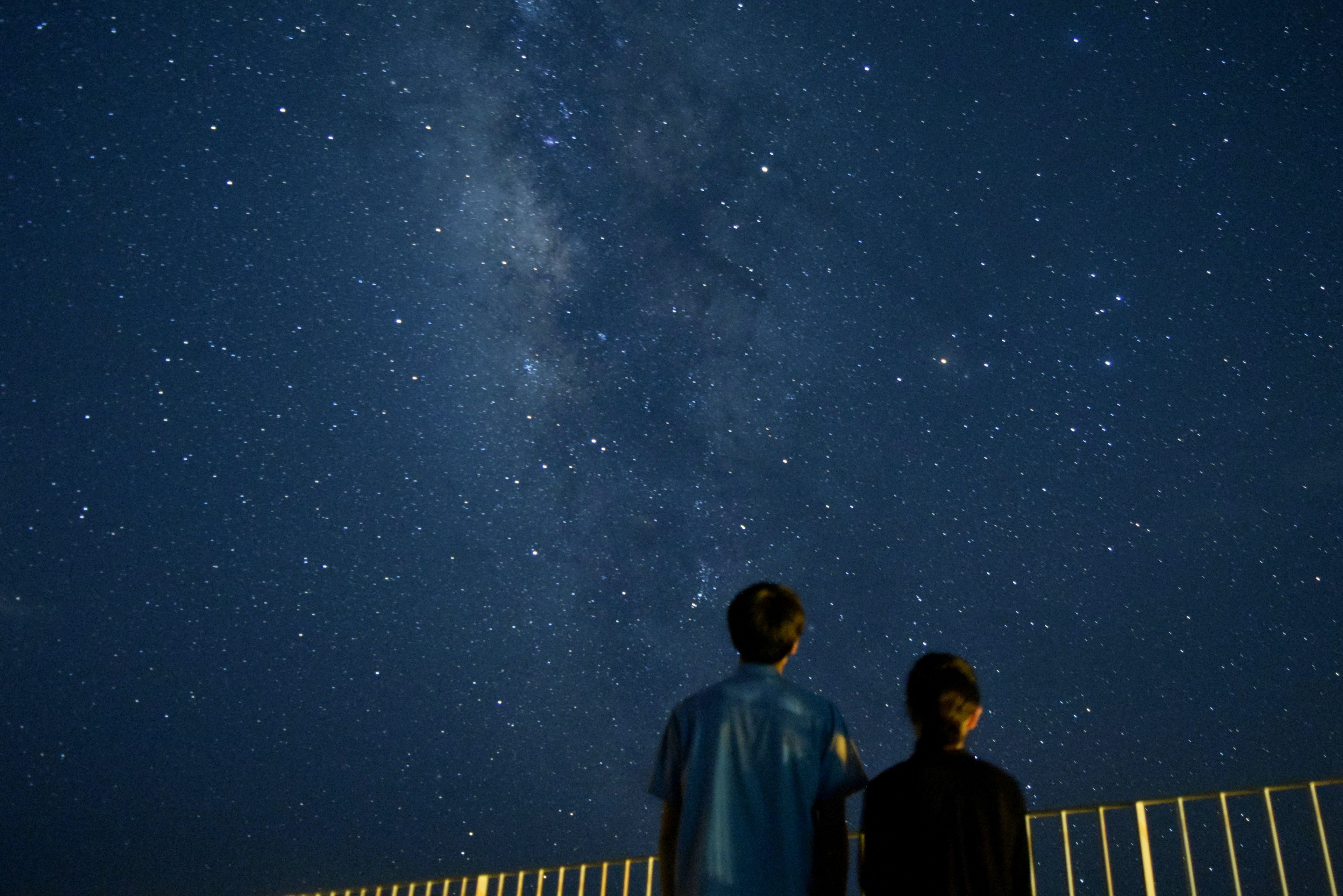 Two people standing under a starry sky.