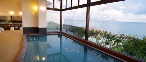 Une piscine avec vue sur la mer et sur un navire au loin.