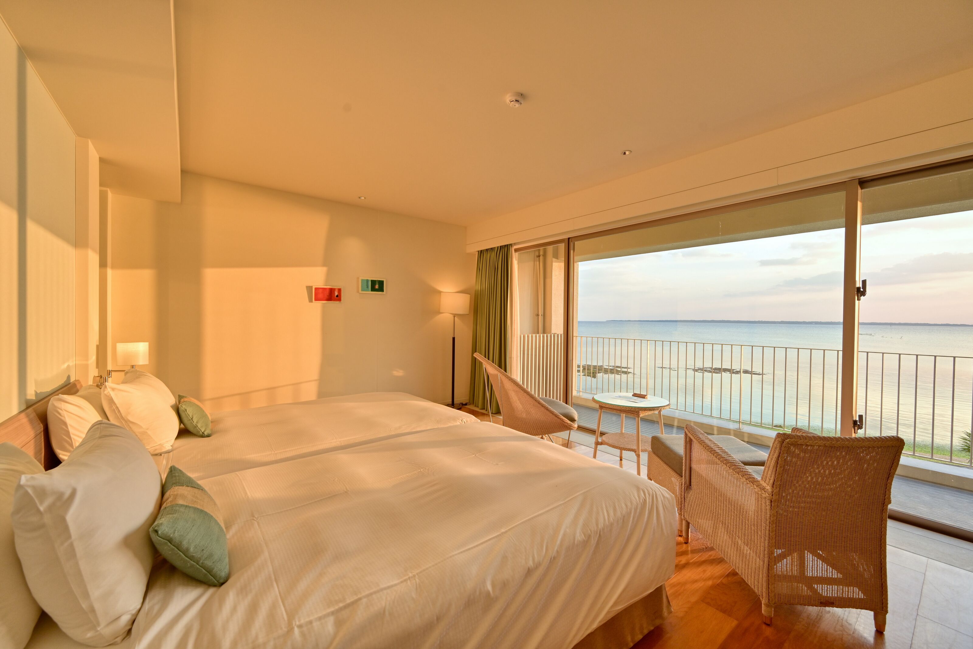Een hotelkamer met een groot bed, een stoel en een balkon met uitzicht op zee.