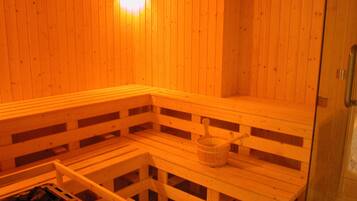 Un sauna avec des bancs en bois et une petite table sur laquelle se trouve un seau.