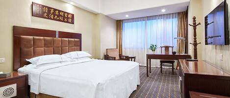 A hotel room with a large bed, a desk, a chair, a television, and a decorative wall piece.