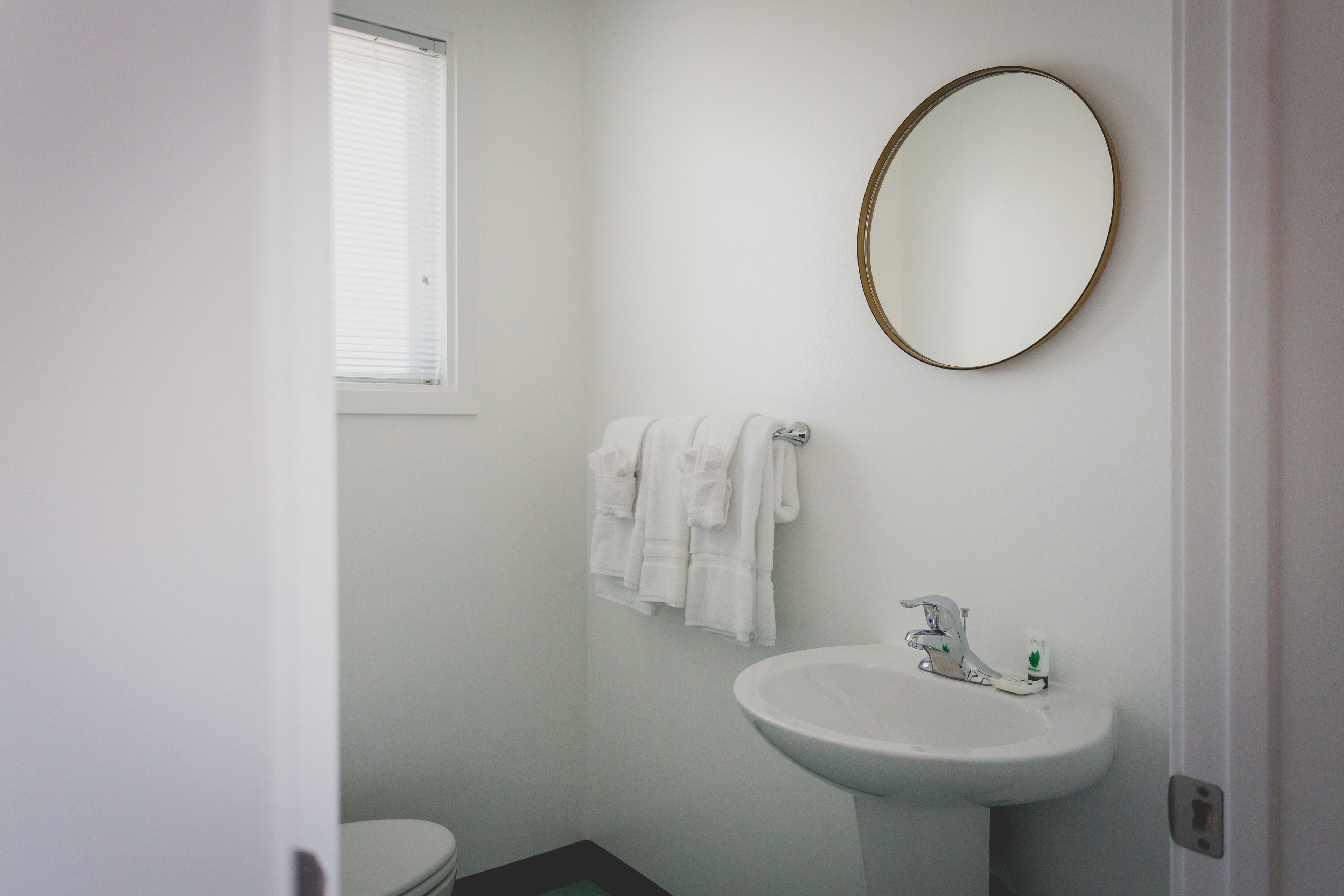 A bathroom with a white sink, a round mirror, and a toilet.