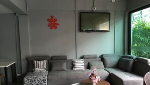 Una sala de estar moderna con un sofá seccional gris, una mesa de centro redonda con un florero y un televisor de pantalla plana montado en la pared.