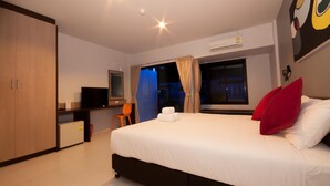 Una habitación de hotel con cama, escritorio, televisor y armario.