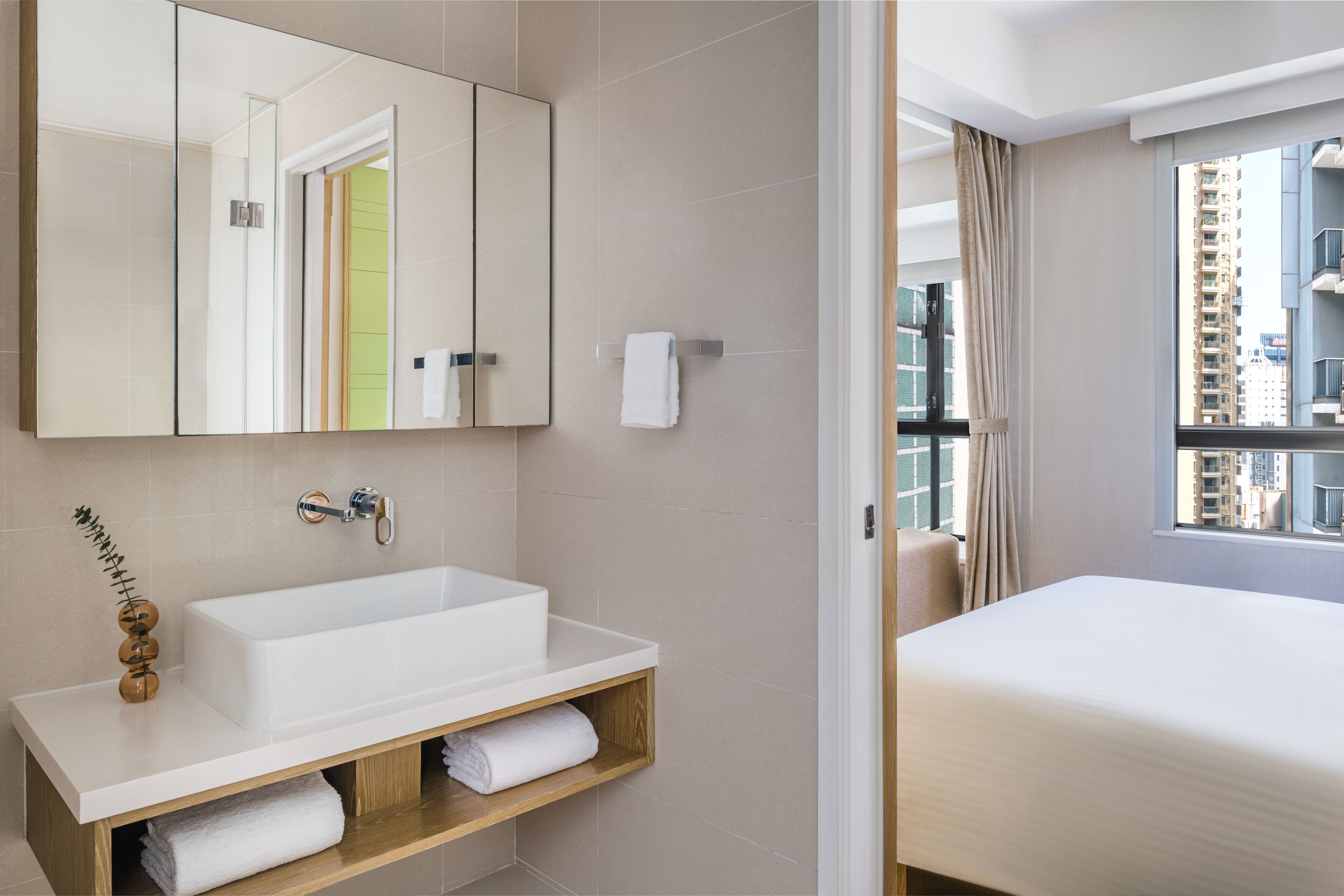 Un baño moderno con un espejo grande, lavamanos blanco y tocador de madera.