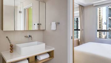 A modern bathroom with a large mirror, white sink, and wooden vanity.