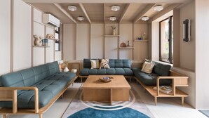 A modern living room with a sectional sofa, a coffee table, and built-in shelving. - Ying’nFlo, Hong Kong, Wan Chai by Langham Hospitality Group (Hong Kong)