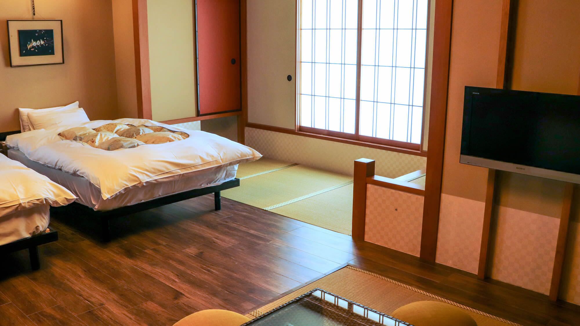 Ein Zimmer mit zwei Betten, einem Tatami-Boden, einem Fernseher und einer Schiebetür.