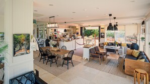 A spacious living area with a dining table, sofas, and a kitchen in the background. - Aria Hotel Jeju (Seogwipo)