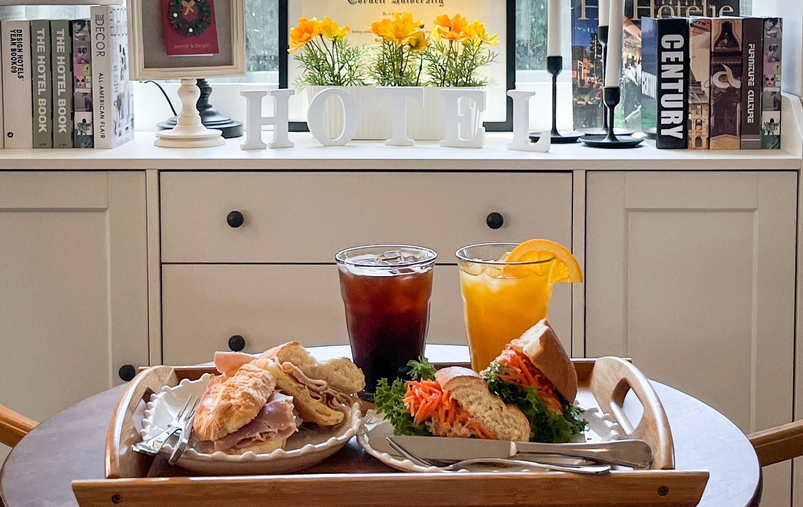A tray with food and drinks on a table, with books and a 'HO' sign in the background.