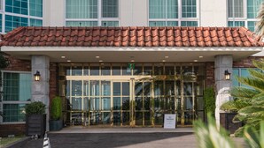 A hotel entrance with a red-tiled roof, large glass doors, and a "NO SMOKING" sign. - Aria Hotel Jeju (Seogwipo)