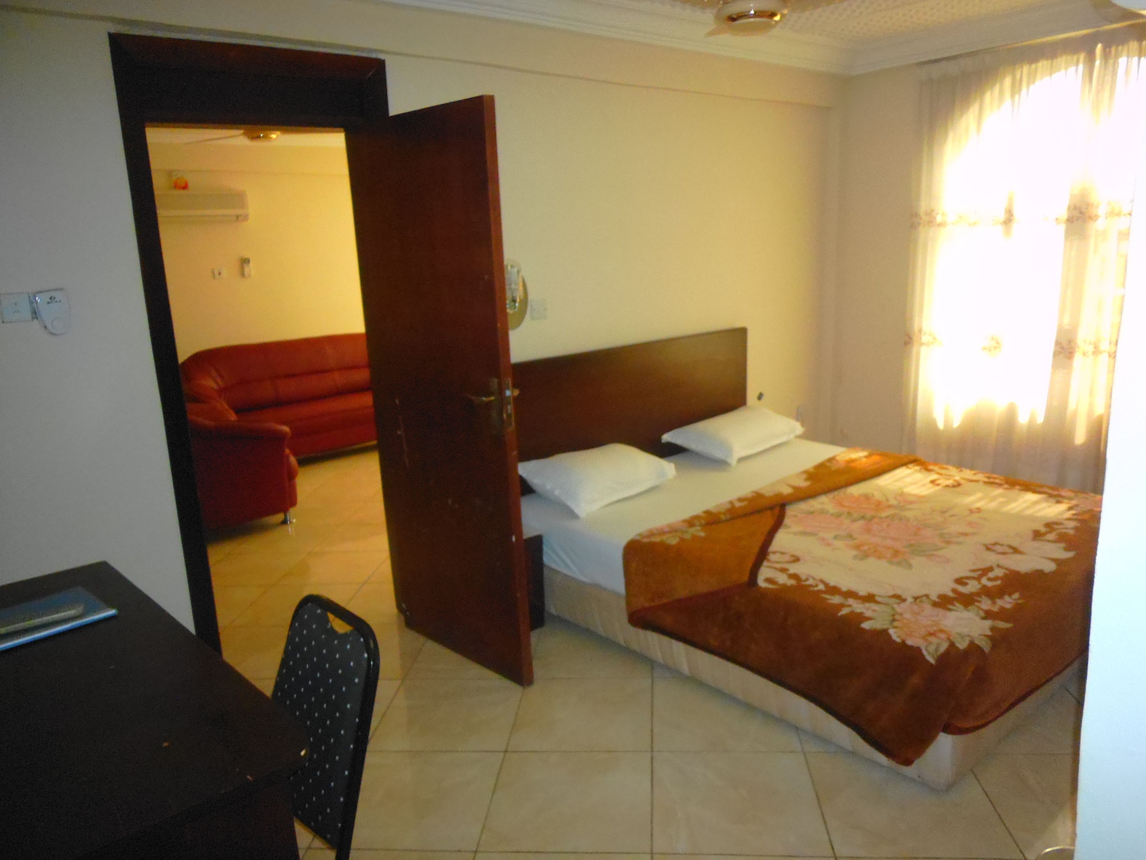 A hotel room with a bed, a desk, and a red sofa.