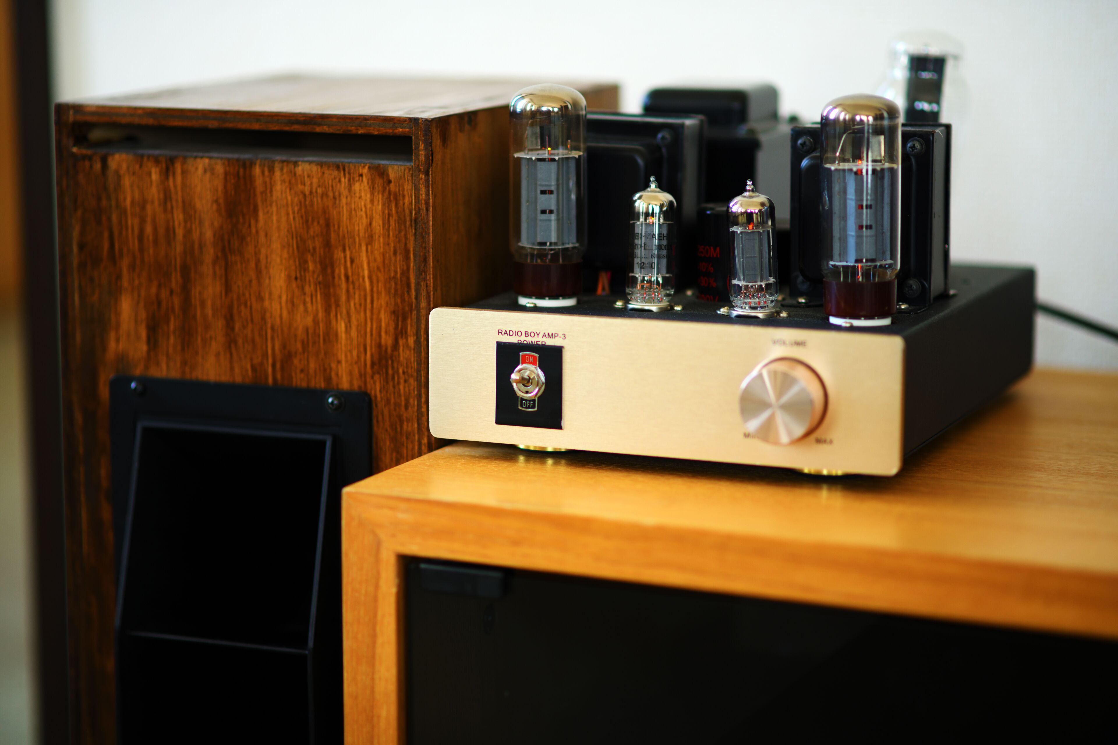 Um armário de madeira com um dispositivo eletrônico preto e um amplificador de rádio vintage em cima.