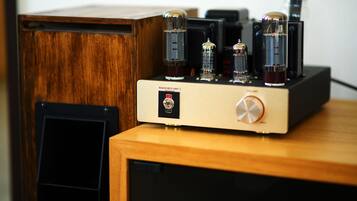 Um armário de madeira com um dispositivo eletrônico preto e um amplificador de rádio vintage em cima.