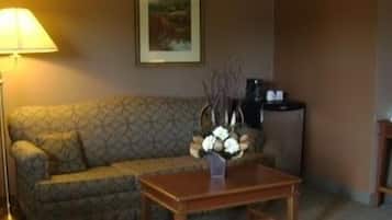 A living room with a patterned sofa, a coffee table, a lamp, and a framed picture on the wall.