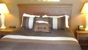 A neatly made bed with a striped pillow, two bedside tables with lamps, and a wooden headboard.