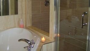 A bathroom with a bathtub, a glass shower enclosure, and a mirror.