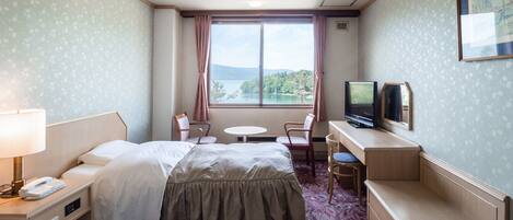 A hotel room with two beds, a desk with a TV, a chair, a small table, and a window with a view of the outdoors.